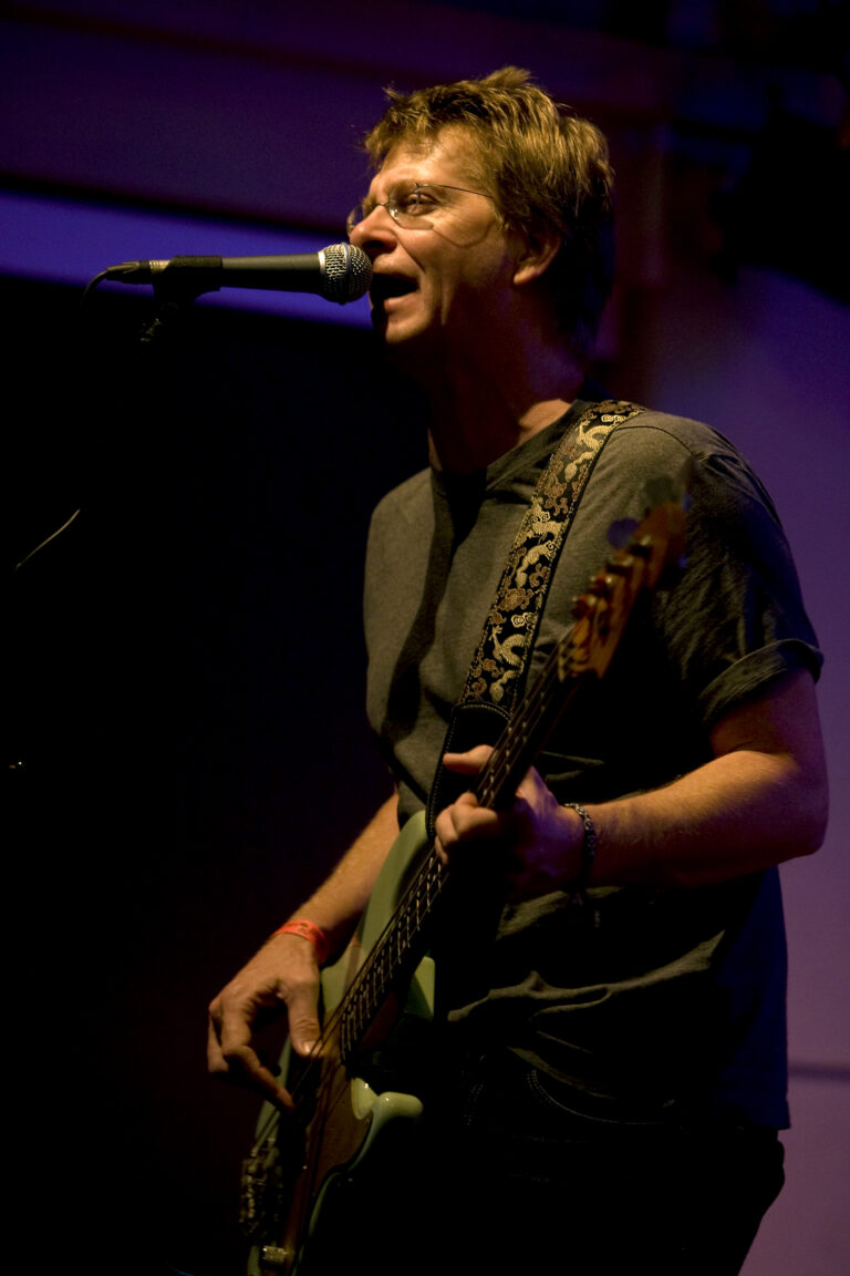 Een muzikant speelt gitaar en zingt in een live optreden met een microfoon.