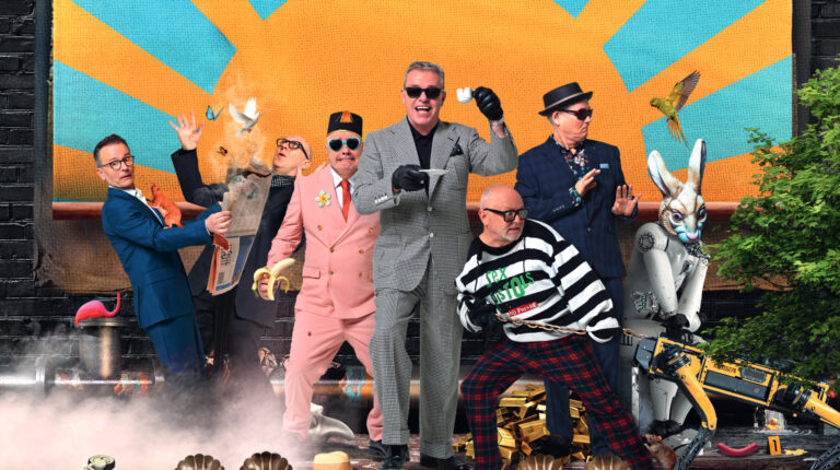 Vrolijke bandfoto van 6 mannen en een robotkonijn met een stuilstaande animatie van de zon op de achtergrond