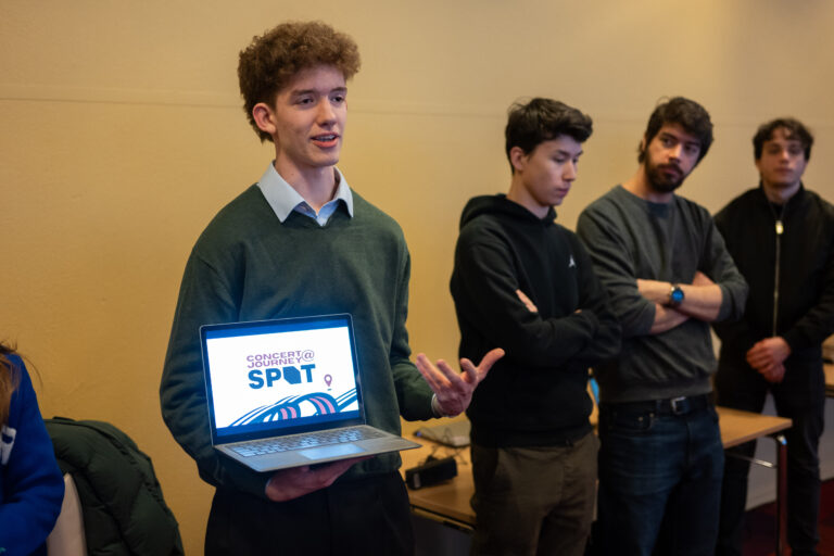 Student met laptop in de hand presenteert staand met medestudenten.