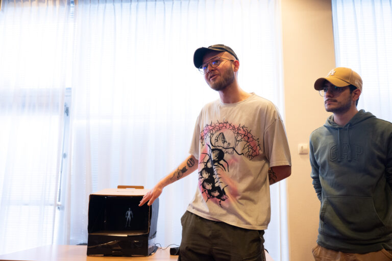 Jongen in wit shirt met pet wijst doos met scherm aan