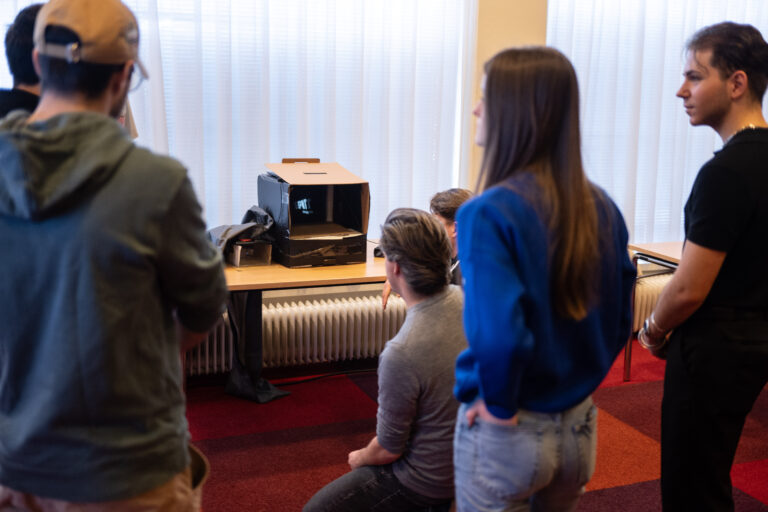 Groep studenten kijkt naar een doos met een scherm erin