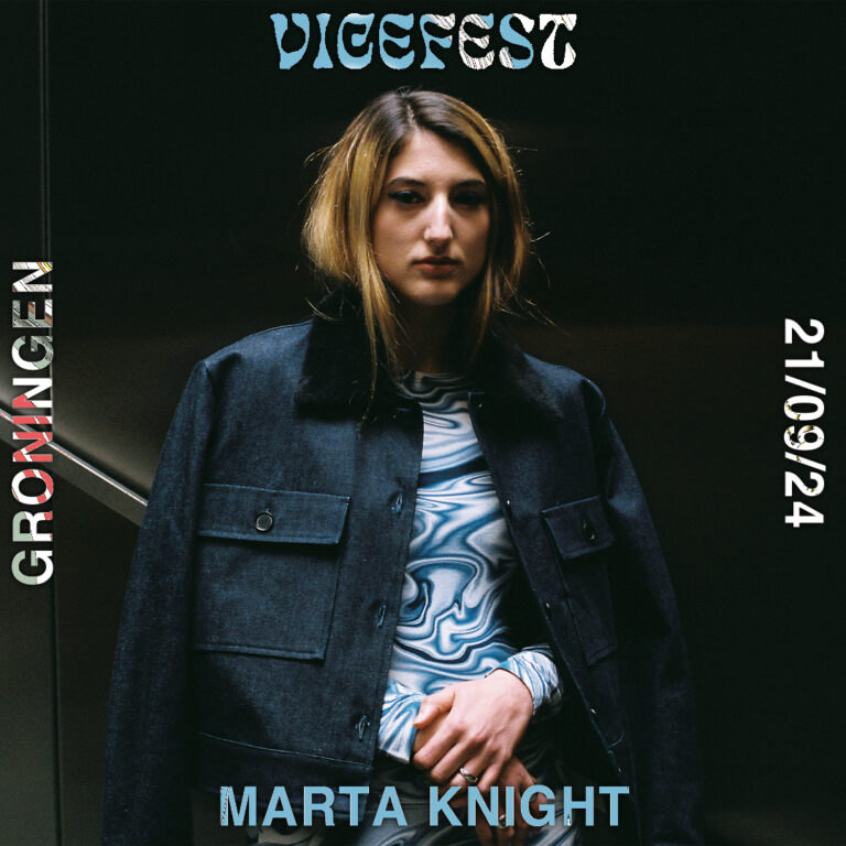 Vrouw met blauwe spijkerjas om haar heen en zwarte achtergrond.