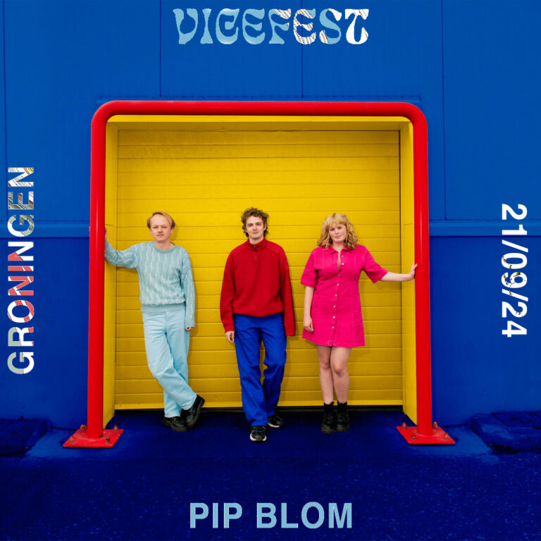 Twee mannen en 1 vrouw staan voor gele garagedeur van een blauw gebouw.