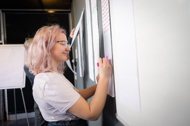 Student met roze haar schrijft idee op het bord