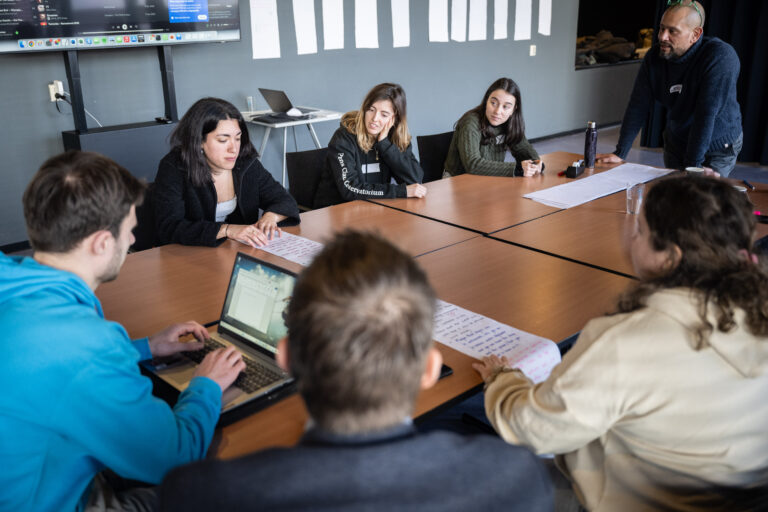 Studenten aan een tafel. In het midden staat een laptop