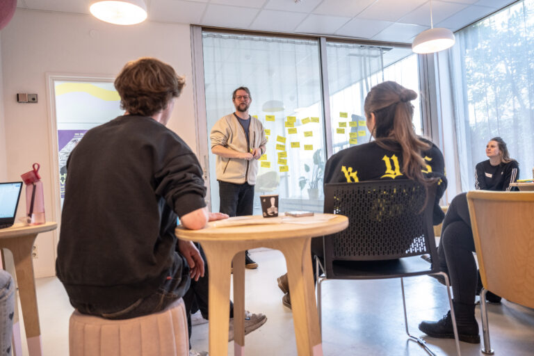 Twee studenten met rug naar de camera die luisteren naar presentatie