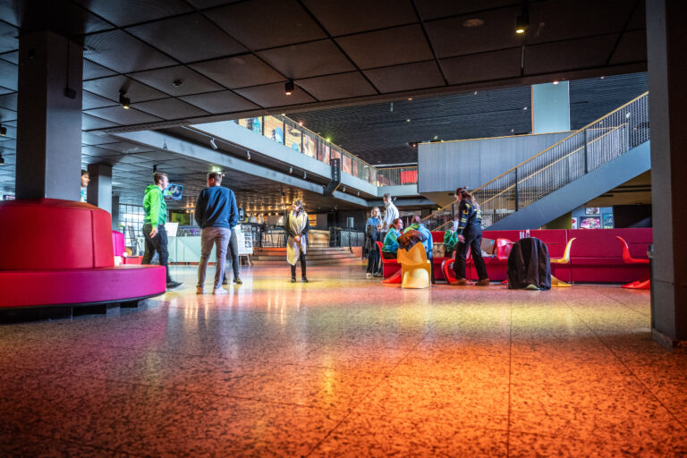 Personen staan in de hal te praten met elkaar