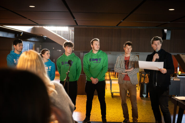 Studenten in groene truien en persoon met microfoon