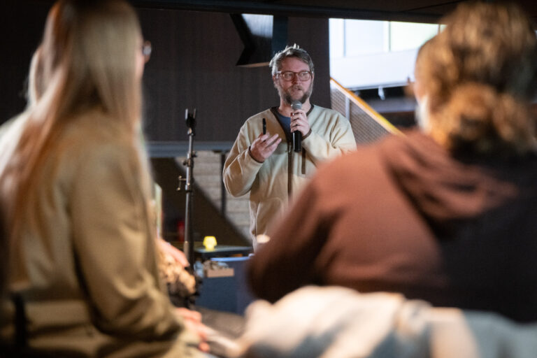 Persoon met microfoon presenteert voor groep studenten