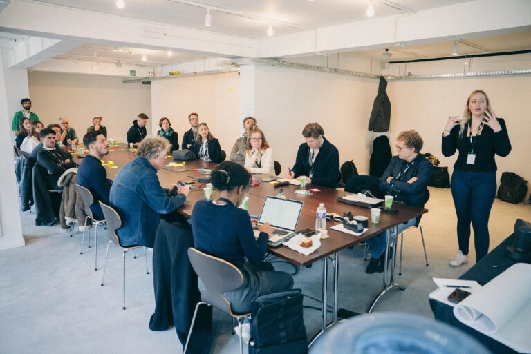mensen in een zaal krijgen presentatie en zitten aan tafel