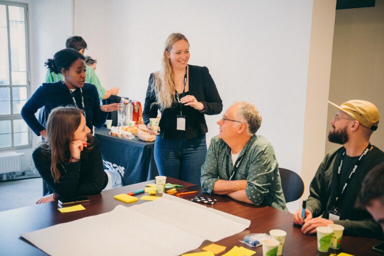 vijf mensen zitten voor het grote papier