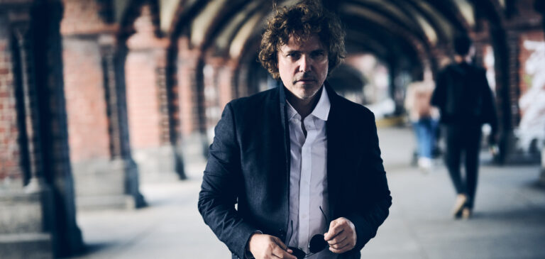 Een man in pak loopt op de camera af op een treinstation