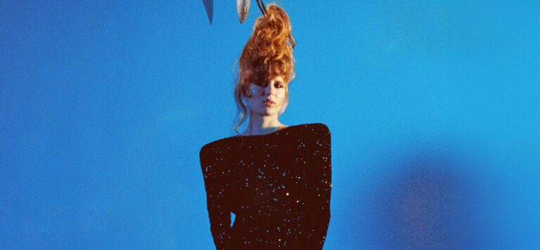 Jonge vrouw oranje haar met haaien ballon vast aan haar haar. Blauwe achtergrond.