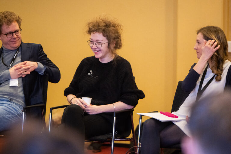 Drie personen met in het midden een vrouw die lacht