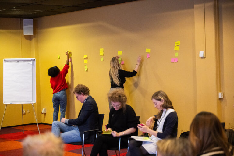 Een groep mensen schrijft op de post its