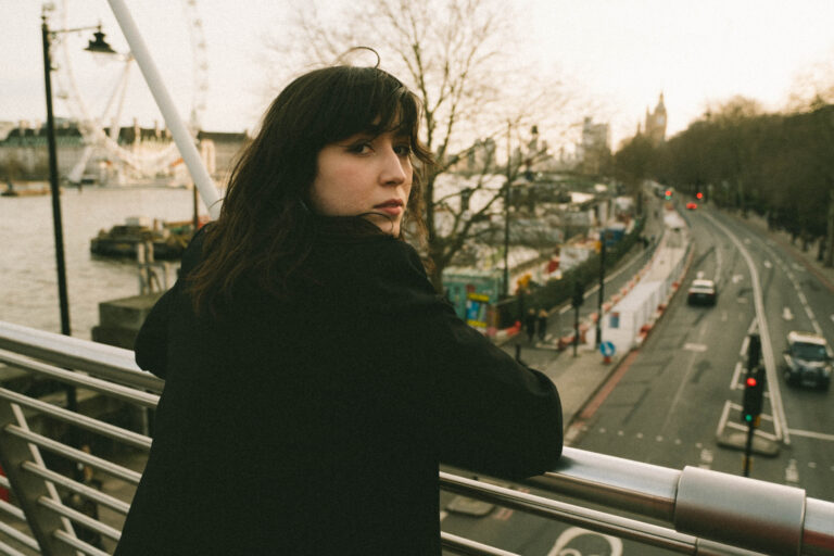 Vrouw donker haar staat op een brug boven autoweg en kijk naar achter.