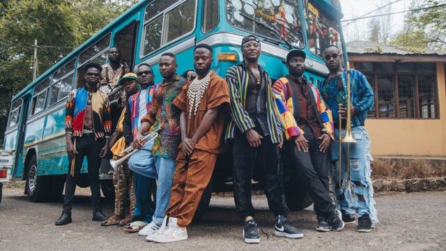 Negen Afrikaanse muzikanten leunen tegen blauwe vintage bus