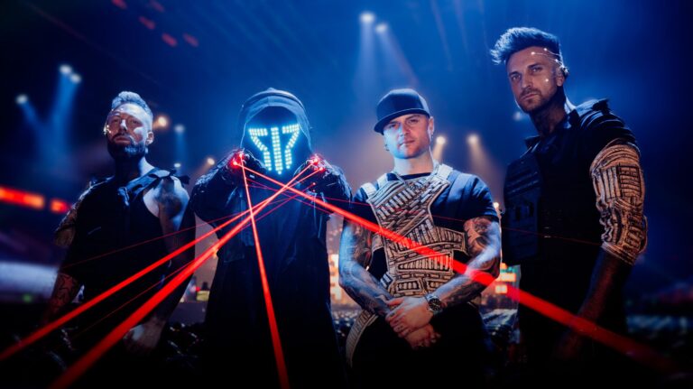 Vier bandeleden in futuristiche outfit waarvan eentje lasrstralenm uit zijn handschoenen stuurt,