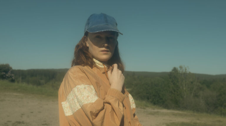 vrouw met oranje jas en blauw petje