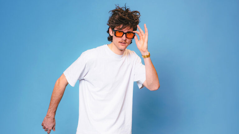 Jongen in wit t-shirt met oranje bril voor een blauwe achtergrond