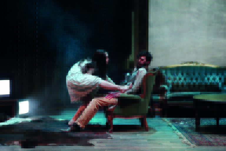 Bange man zit op een stoel terwijl een vrouw met een wit gezicht en witte jurk op hem klimt