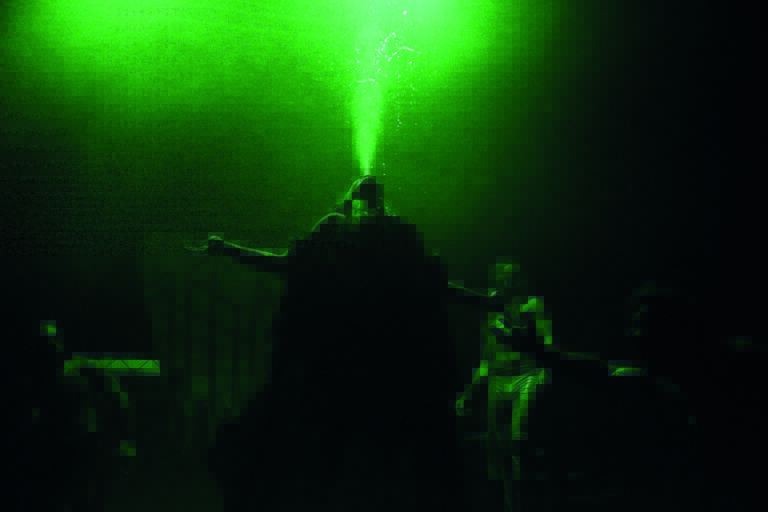 Een silhouet van een persoon die een groene laserstraal in de lucht richt.