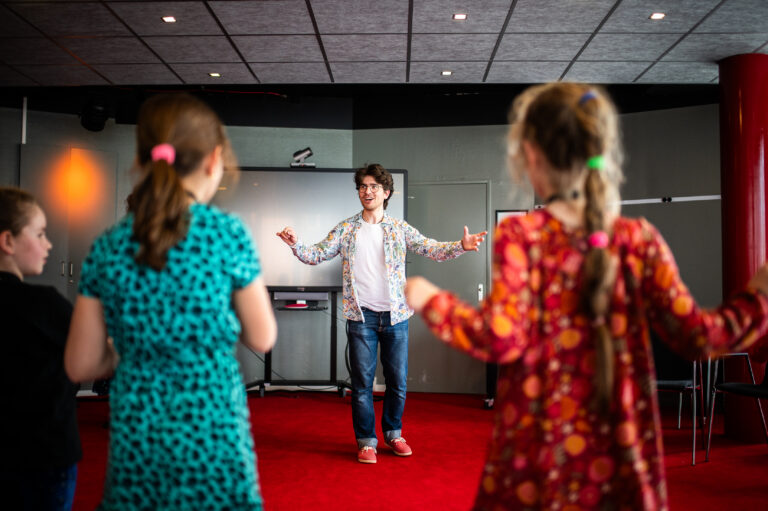 Muziekdocent voor een groep kinderen tijdens de kindermuziekweek
