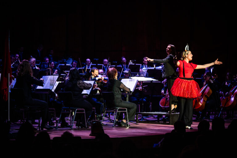 Actrice in rode jurk tijdens het concert Carmen door het Noord Nederlands Orkest
