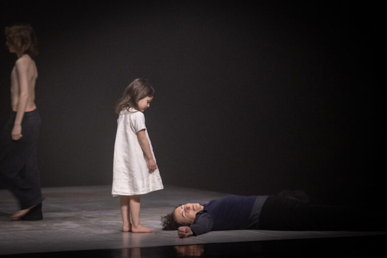 Klein meisje in witte jurk kijkt naar een volwassen persoon met gesloten persoon die aan haar voeten ligt