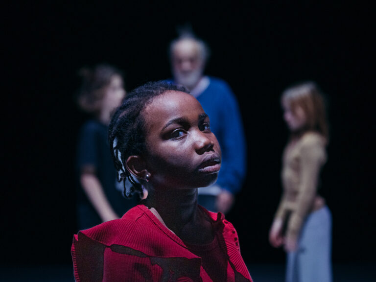 Meisje met rode vlechten met op achtergrond een oudere man en twee jongeren