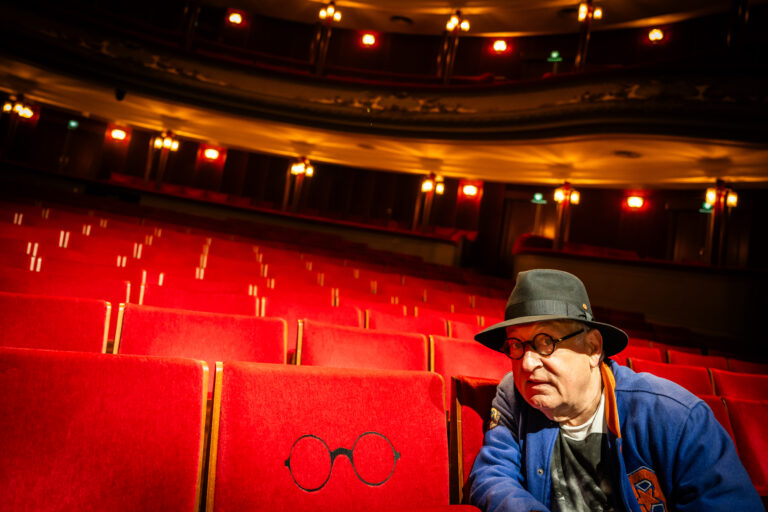 Youp van't Hek naast zijn eigen stoel in de Stadsschouwburg