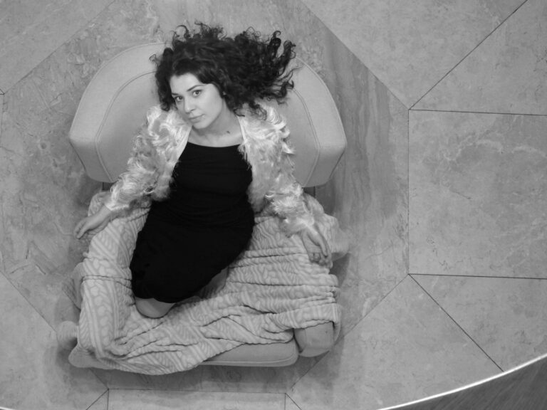 Vrouw ligt in een lichte stoel en kijkt naar boven op zwart witte foto.