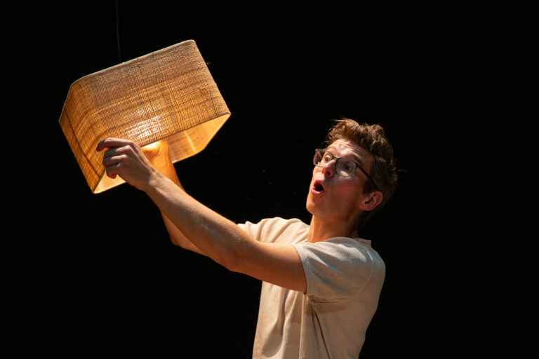 Remy staat op het podium in een wit t-shirt te zwaaien met een mandje