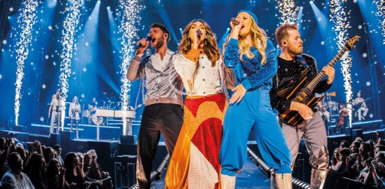 Een live optreden van vier muzikanten op een podium, omgeven door vuurwerk en een enthousiast publiek.