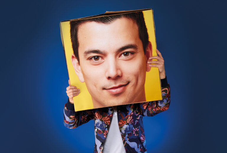 Andries houdt een grote versie van zijn hoofd op karton voor zijn hoofd