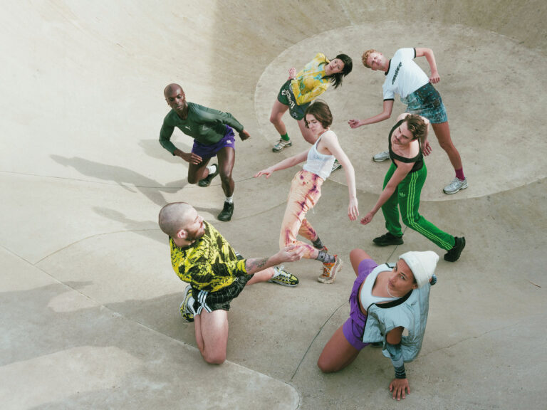 Groep hippe dansers in kleurlijke street gear dansen op een skatebaan.