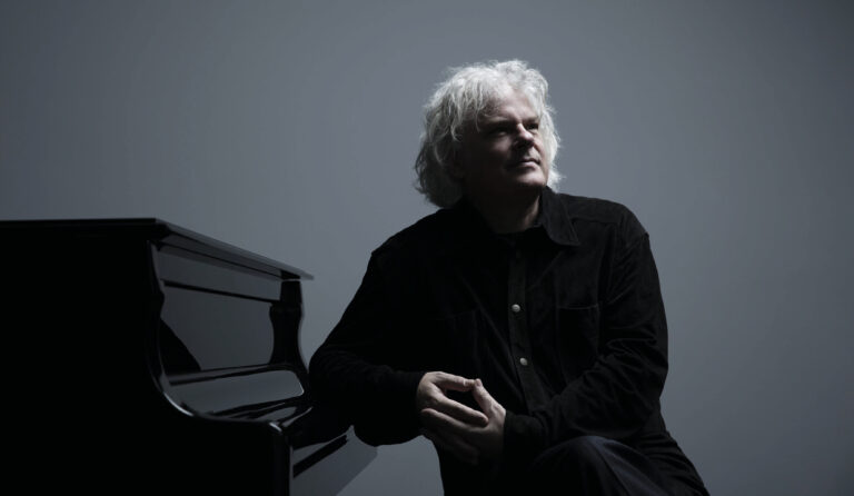 Ronald voor de piano met een grijze achtergrond