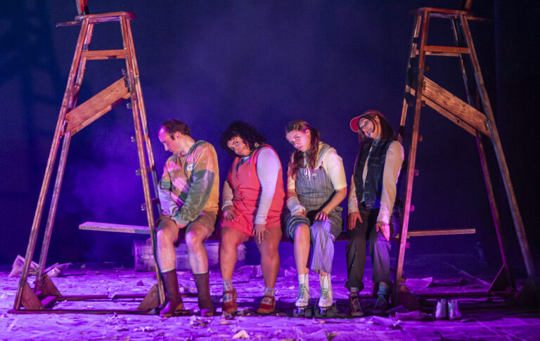 Vier acteurs verkleed als pubers zitten op een rijtje met gebogen rug, kijken in camera.