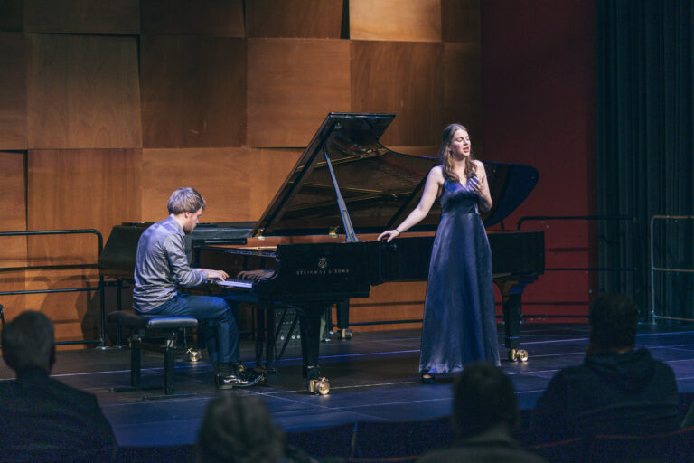 Zanegres (met haar rechterhand leunend op de vleugel) en pianist