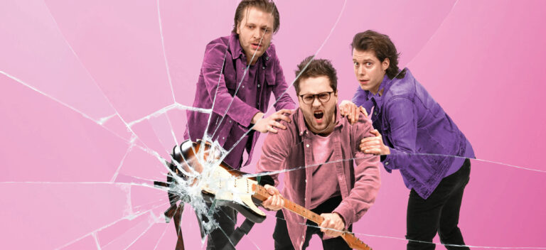 Een lid van de groep slaat met gitaar spiegel kapot terwijl de andere twee hem vasthouden