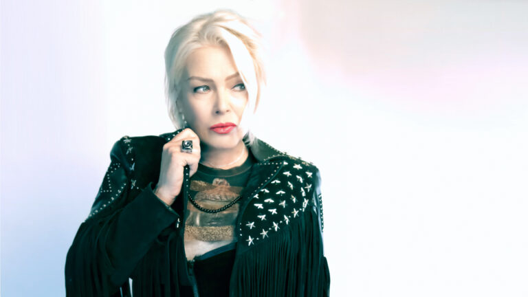 Kim Wilde voor lichte achtergrond met zwarte jas aan