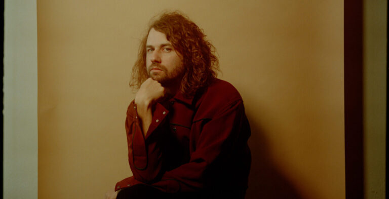 kevin morby voor een gele muur