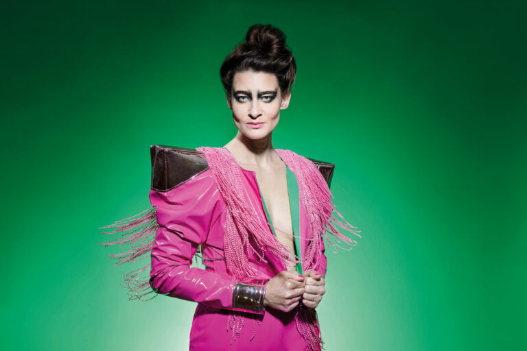 Portretfoto van Kirsten met een stoere blik en roze powerkleren met hoekige schouders