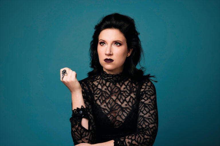 Portretfoto waarin Lotte met kantenkleding en donkere lippen naar boven staart met hand onder haar ellenboog