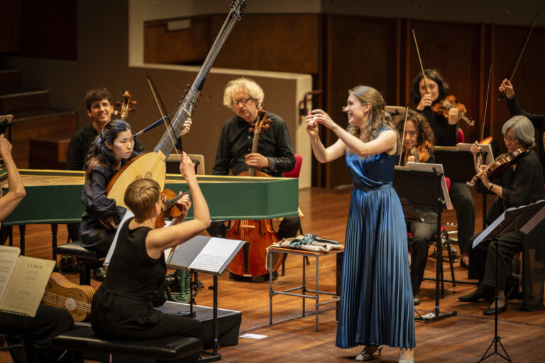Lucie Horsch in een blauwe jurk vanaf de zijkant