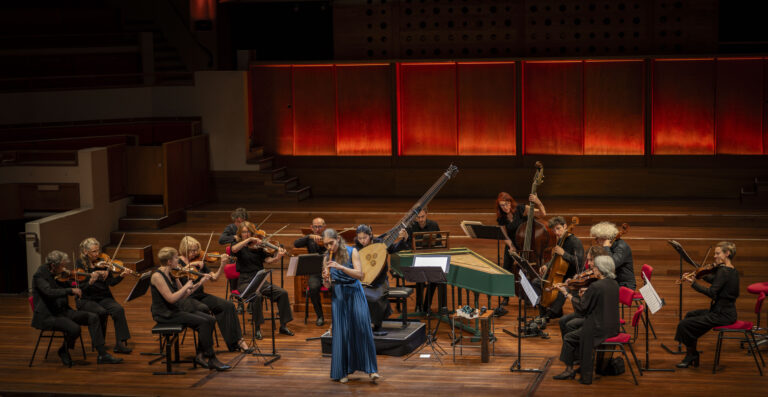 Lucie Horsch in een blauwe jurk vanaf de voorkant speelt op blokfluit