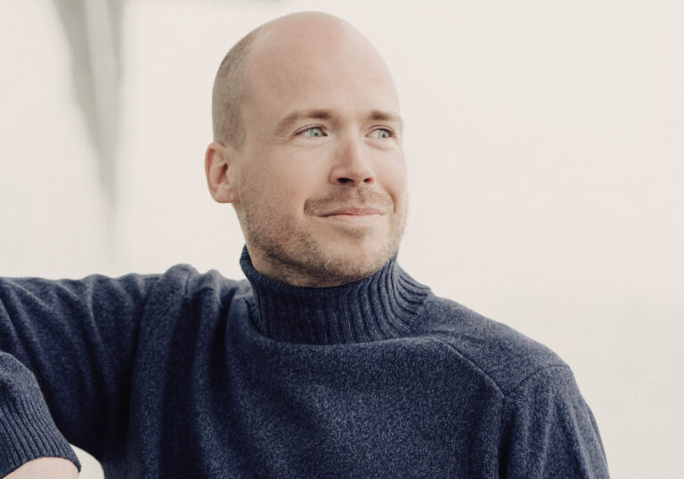 Portretfoto van Maarten Engeltjes in een donkere coltrui met een lichte achtergrond kijkend naar rechts