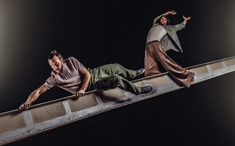 Twee perfomers proberen op een horizontale balk te blijven