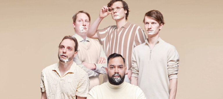 Peter en band allemaal in beige kleding met taart of slagroom rond hun mond