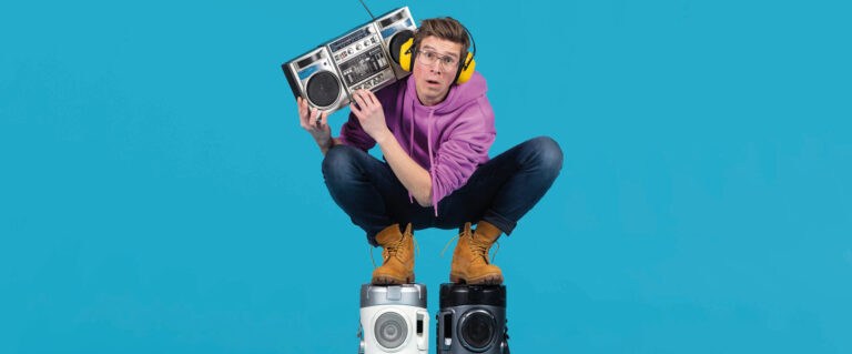 Remy staat met een oudere boombox en koptelefoon op 2 boomboxen